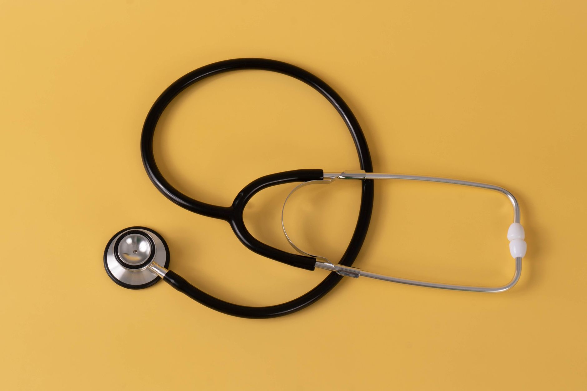 Close-up of a black stethoscope on a vibrant yellow surface, ideal for medical themes. — Female Hair Decline: What Sepia Can