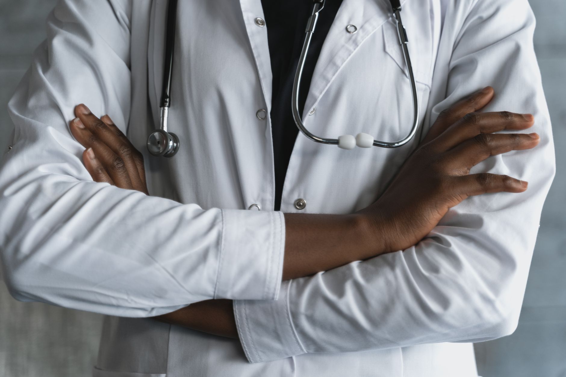 Close-up of a confident doctor in a lab coat standing with crossed arms and stethoscope. — Hair Discount Strategies for the Y