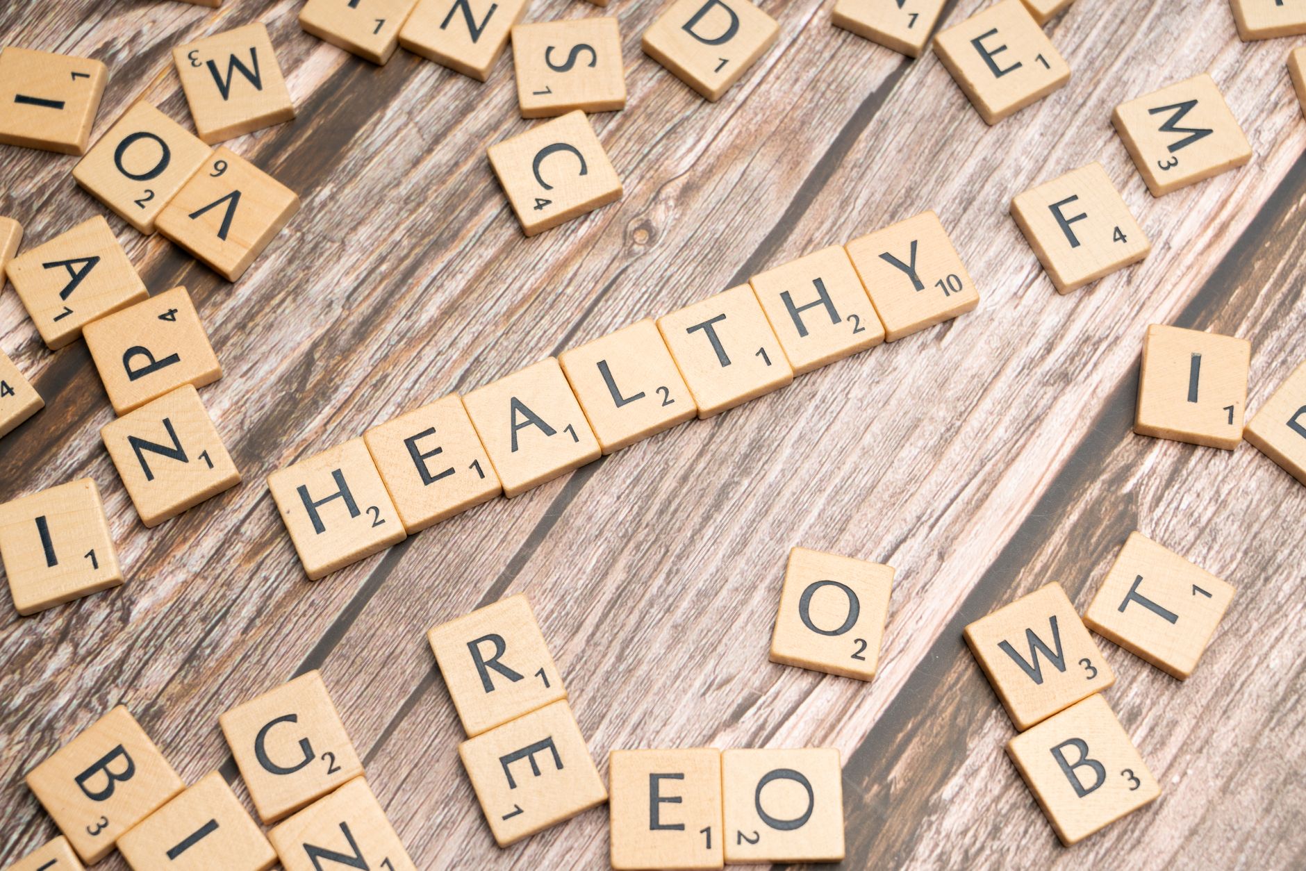 Wooden letter tiles arranged on a wooden surface spelling out 'healthy', symbolizing wellness. — Largest Distinction Regardin