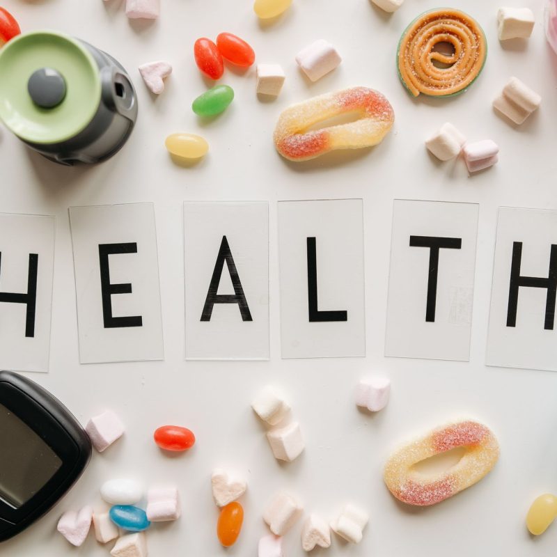 Creative flat lay with sweets around a 'HEALTH' text and monitoring device, symbolizing diabetes awareness. — Provillus Hair