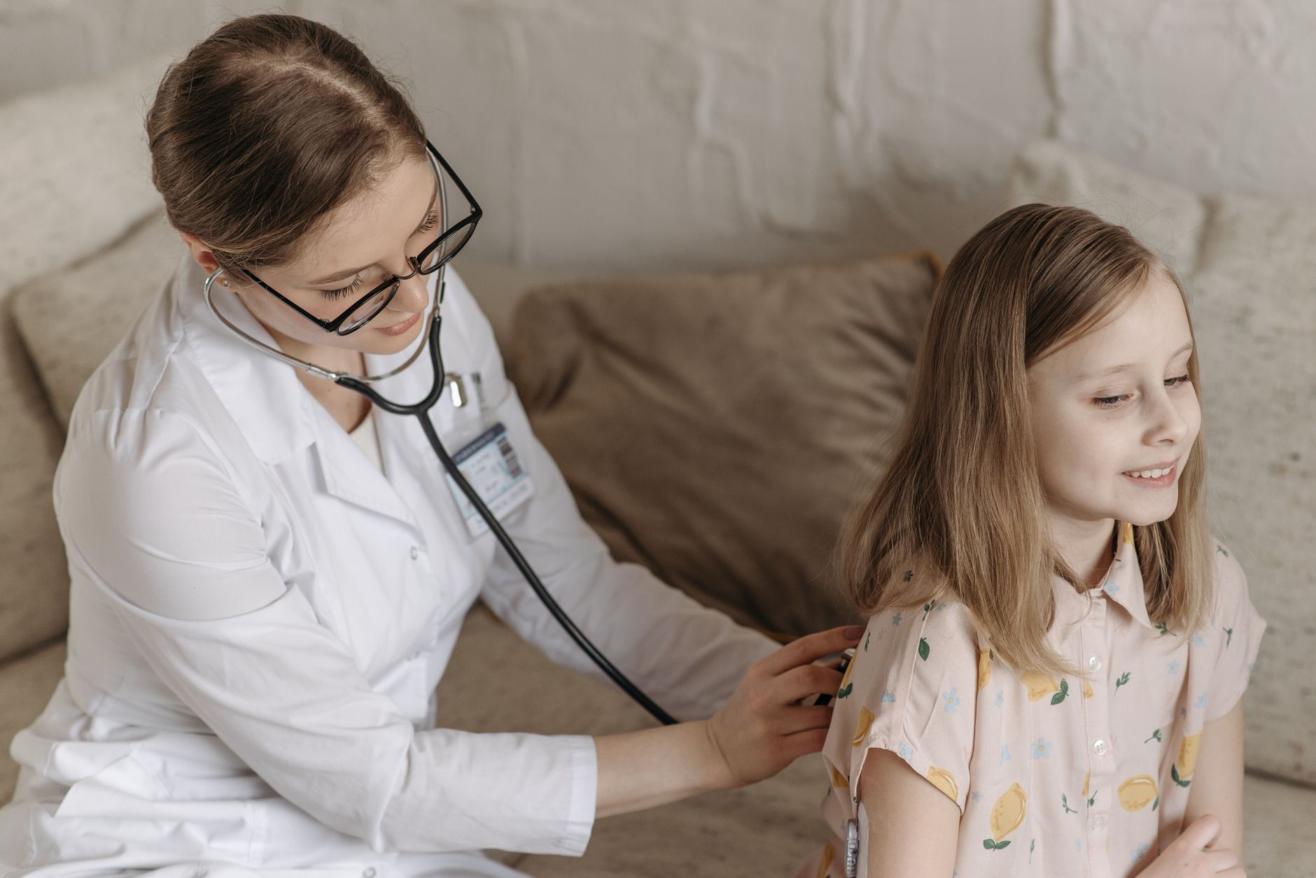 A doctor with a stethoscope examining a smiling girl during a medical check-up at home. — Uncomplicated Meditation Ways